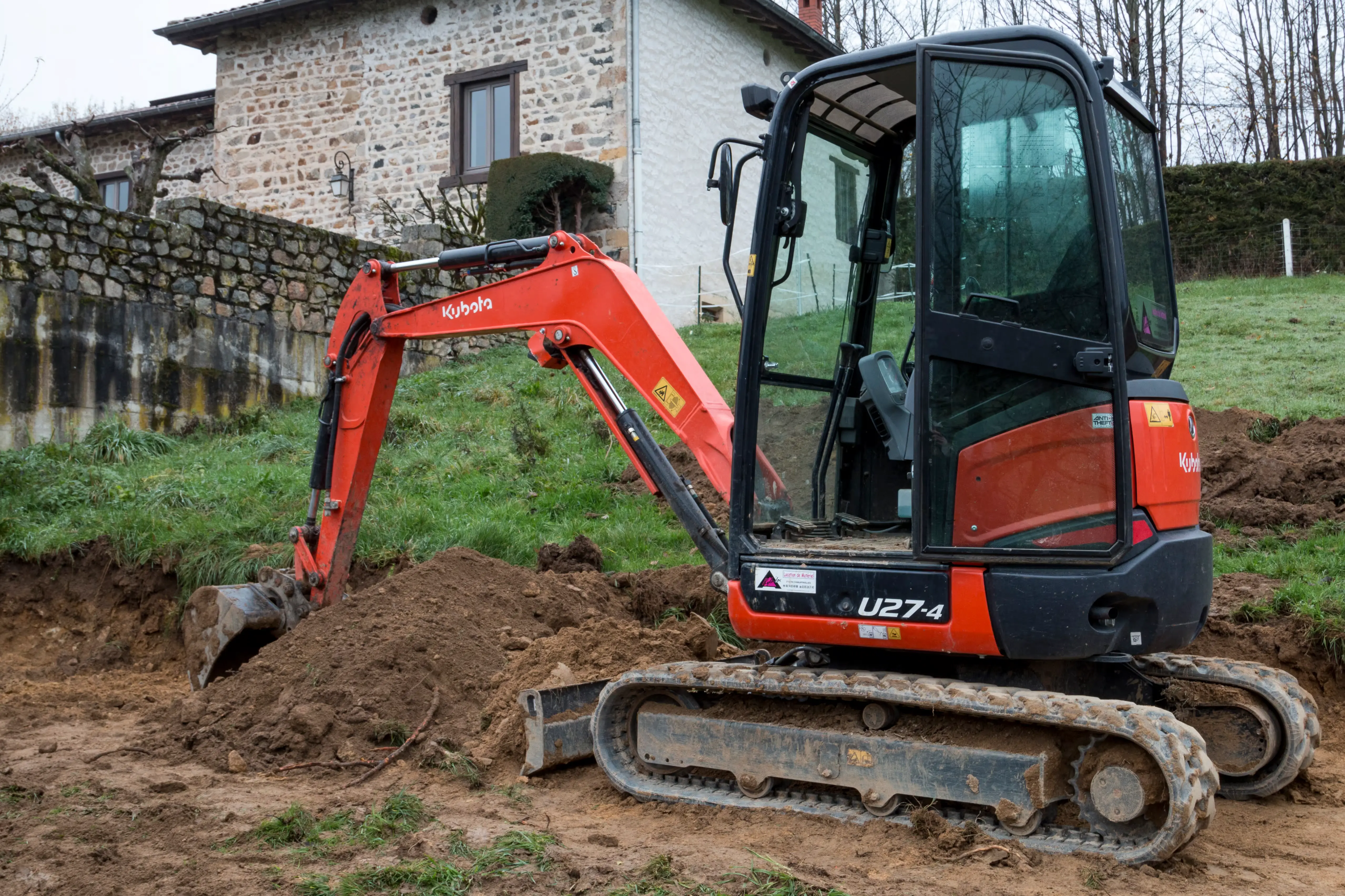 Compact Kubota U27-4 mini excavator working in a tight-access Algarve garden with clean grading